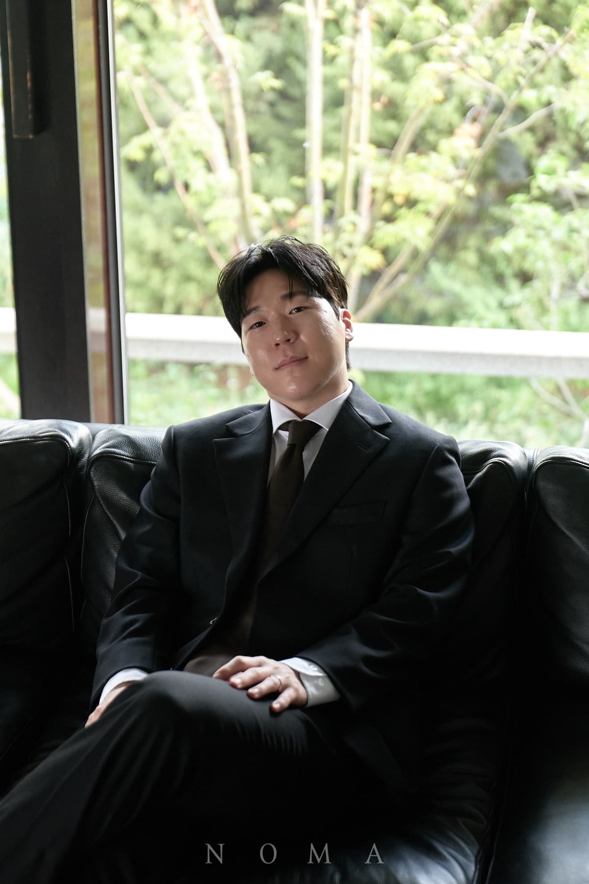 검은 정장을 입고 창가 가죽 소파에 앉은 형준